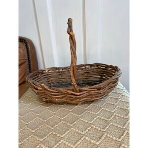rustic vintage woven twig gathering basket with a tall handle.